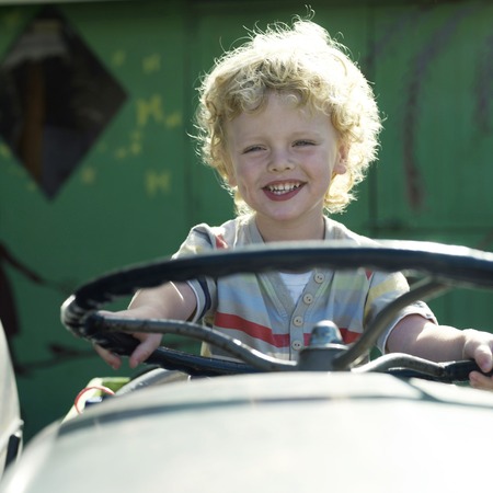 Boy sitting on tractor, smilingの写真素材