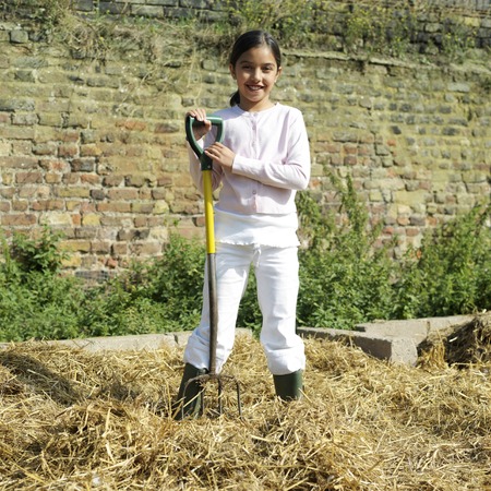 Girl with rubber boots holding a pitchforkの写真素材