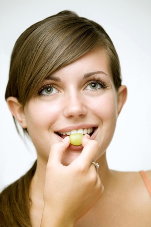 Girl eating green grapeの写真素材