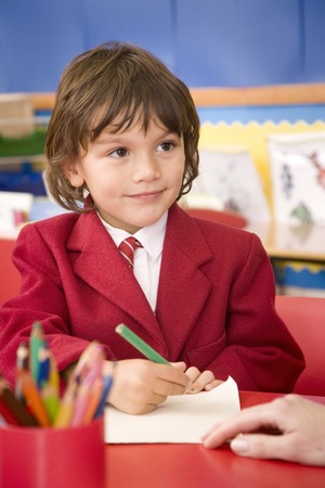 Boy smiling while holding coloured pencilの写真素材
