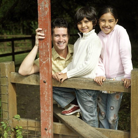 Man, boy and girl posing for the camera at the wooden fenceの写真素材