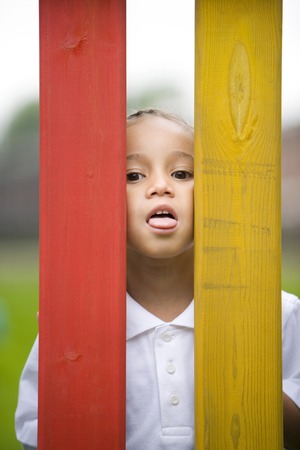 Girl peeking through fences, sticking out her tongueの写真素材