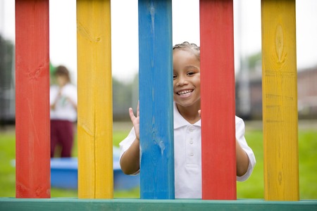 Girl peeking through fences, smiling at the cameraの写真素材