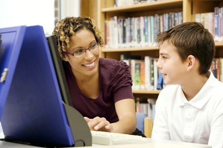 Woman assisting boy using a computerの写真素材