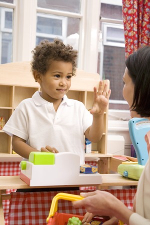 Boy gesturing while playing with toys, woman carrying basketの写真素材