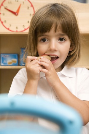 Girl biting on toy hot dogの写真素材