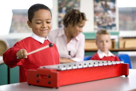 Woman talking to her student while another boy is playing the xylophoneの写真素材