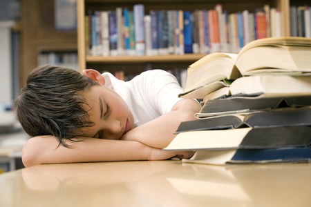 Boy sleeping beside a stack of booksの写真素材