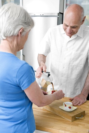 Senior man pouring coffee into senior woman's cupの写真素材