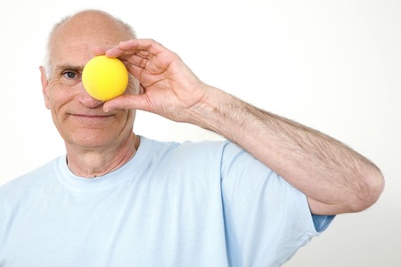 Senior man with an orange covering his eyeの写真素材
