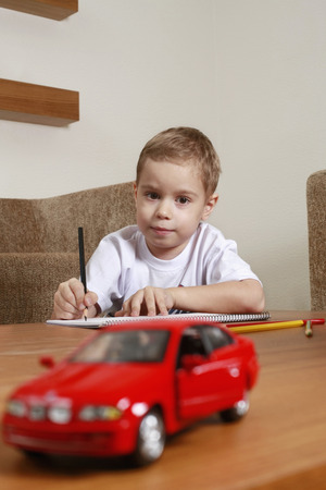 Boy looking at toy car while drawingの写真素材