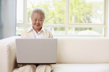 Senior woman using laptop, smilingの写真素材