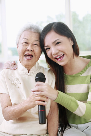 Woman and senior woman singing into the microphonesの写真素材