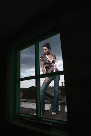 Woman posing for the camera, view through the windowの写真素材