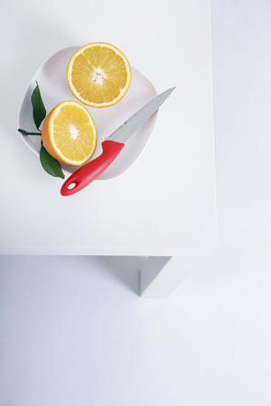 Two halved oranges and knife on a plateの写真素材