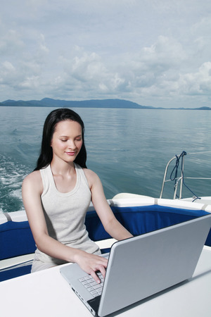 Woman using laptop on yachtの写真素材