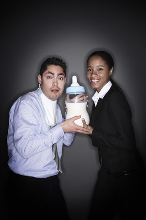 Businessman and businesswoman posing with a giant milk bottleの写真素材