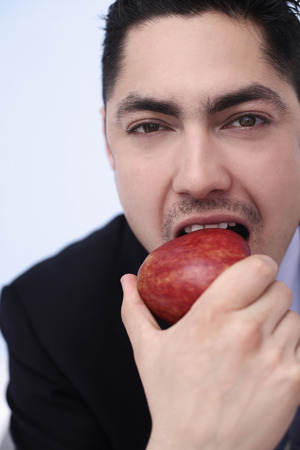 Businessman biting on a red appleの写真素材