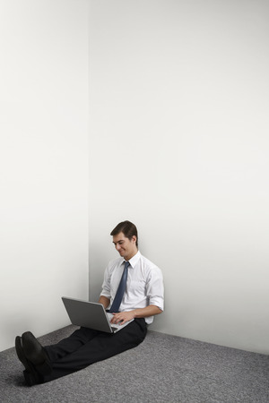 Businessman sitting on the floor using laptopの写真素材