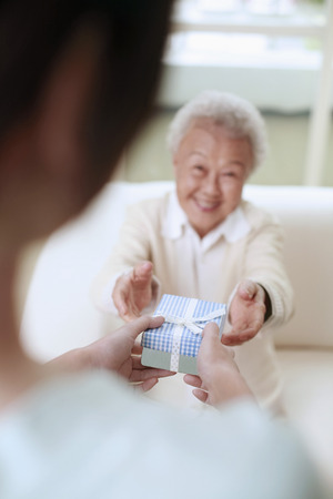 Woman giving senior woman a box of gift