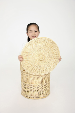 Girl hiding inside laundry basketの写真素材