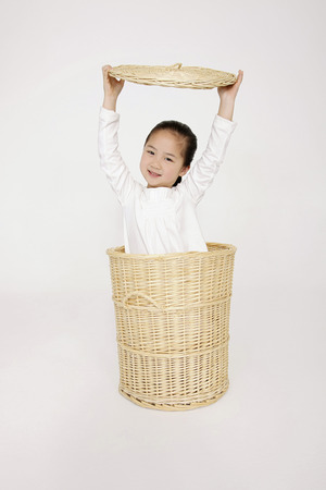 Girl hiding inside laundry basketの写真素材