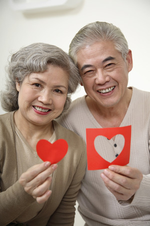Senior woman and senior man holding papers with heart shapeの写真素材