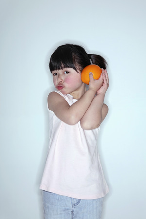 Girl holding orange, pouting her lipsの写真素材