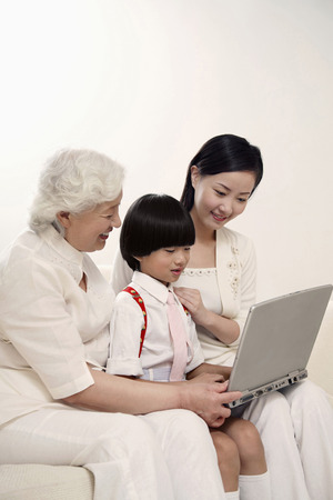 Boy using laptop, woman and senior woman watchingの写真素材