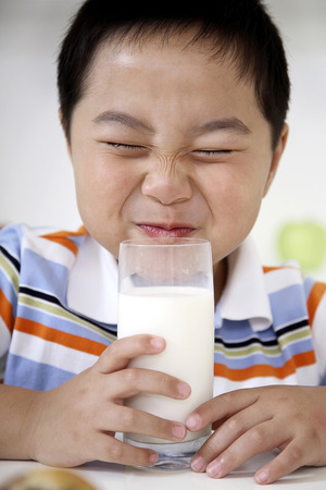 Boy closing his eyes before drinking glass of milkの写真素材