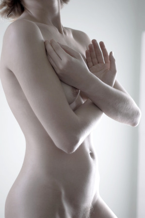 A naked woman covering her breasts with her handsの写真素材