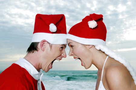 Side shot of a guy and lady in Santa suit screaming at each otherの写真素材