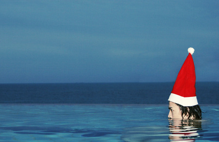 Side shot of a guy in a Santa hat staying in the water with half of his head jerking outの写真素材