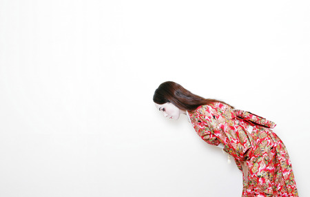 side shot of a woman in red kimono bowing の写真素材