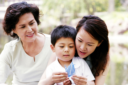 A woman teaching her son how to fold a paper bird の写真素材