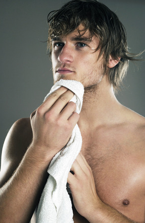 Muscular man wiping his face with a towelの写真素材