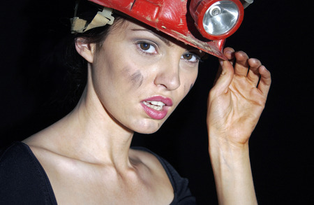 Woman with dirty face wearing a safety helmet の写真素材