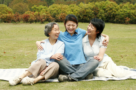 A lady sitting between her mother and grandmother in the parkの写真素材