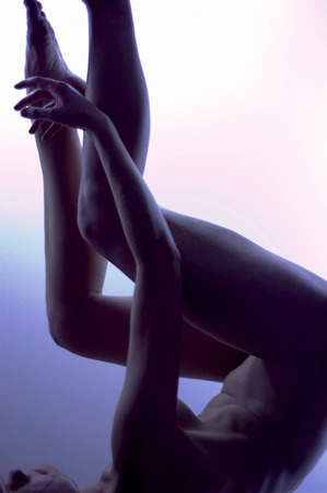 A naked woman lying on her back with her legs upの写真素材