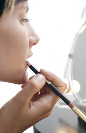 Side shot of a woman applying lip liner の写真素材