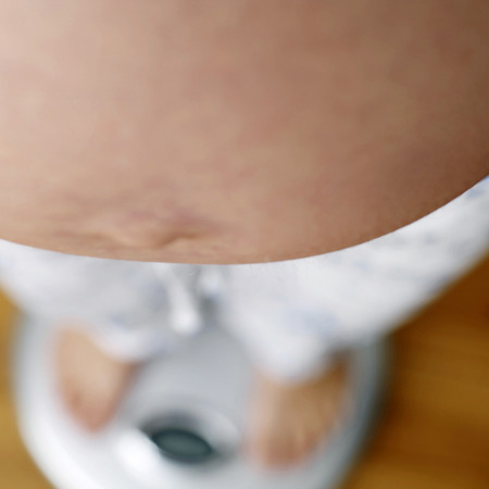 Pregnant woman standing on bathroom scaleの写真素材