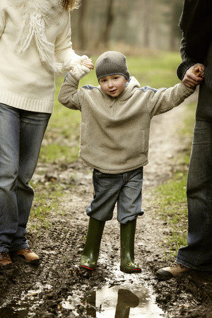 Boy holding parents' handsの写真素材