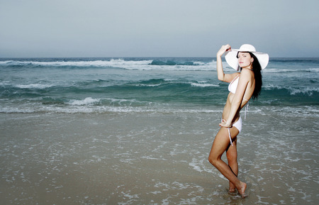 Woman in bikini and hat posing for the cameraの写真素材