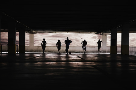 Men and woman playing soccer in parking lotの写真素材
