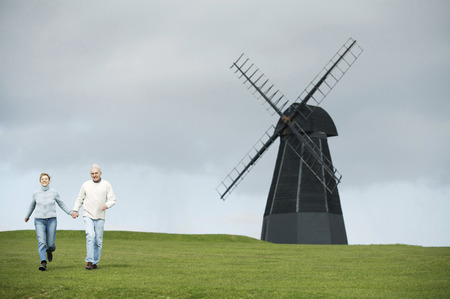 A couple holding hands and walking near a windmillの写真素材