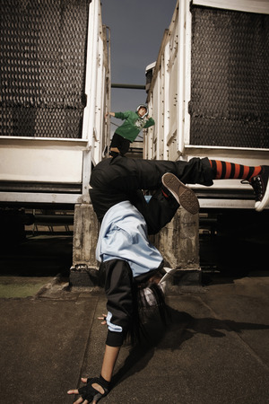 Young woman breakdancing, young man posing in the backgroundの写真素材
