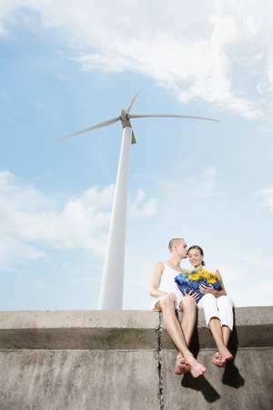 Woman holding a bouquet of flowers with man kissing her on the foreheadの写真素材
