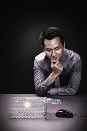 Businessman waiting for computer mouse to get into mouse trapの写真素材