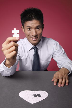 Businessman holding the final piece of jigsaw puzzleの写真素材