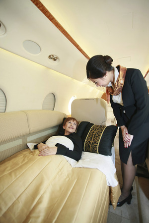 Flight attendant checking on resting businesswoman